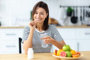 Woman holding vitamin pill and glass of water